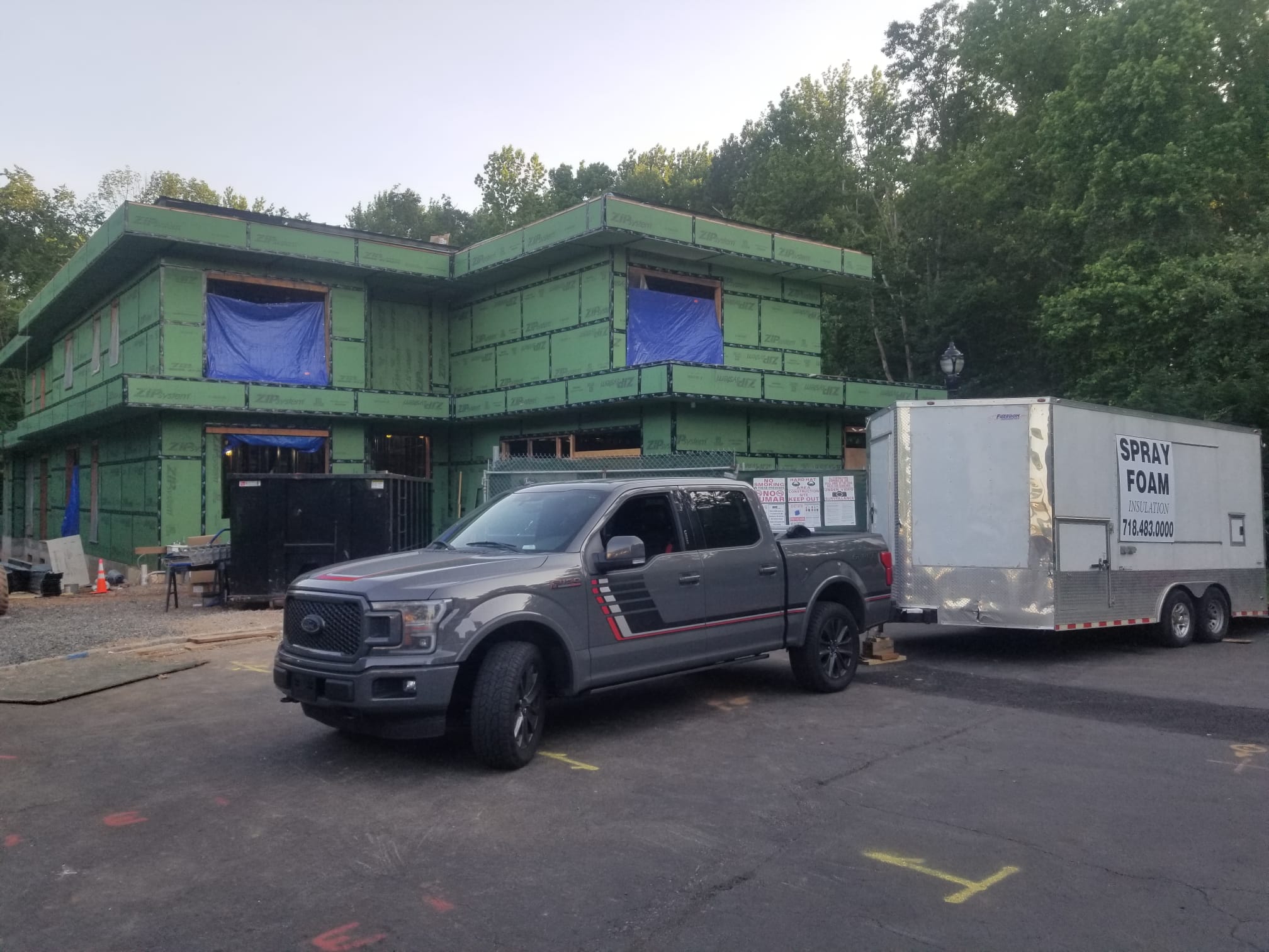 Puza Construction pickup and spray foam trailer outside a new building