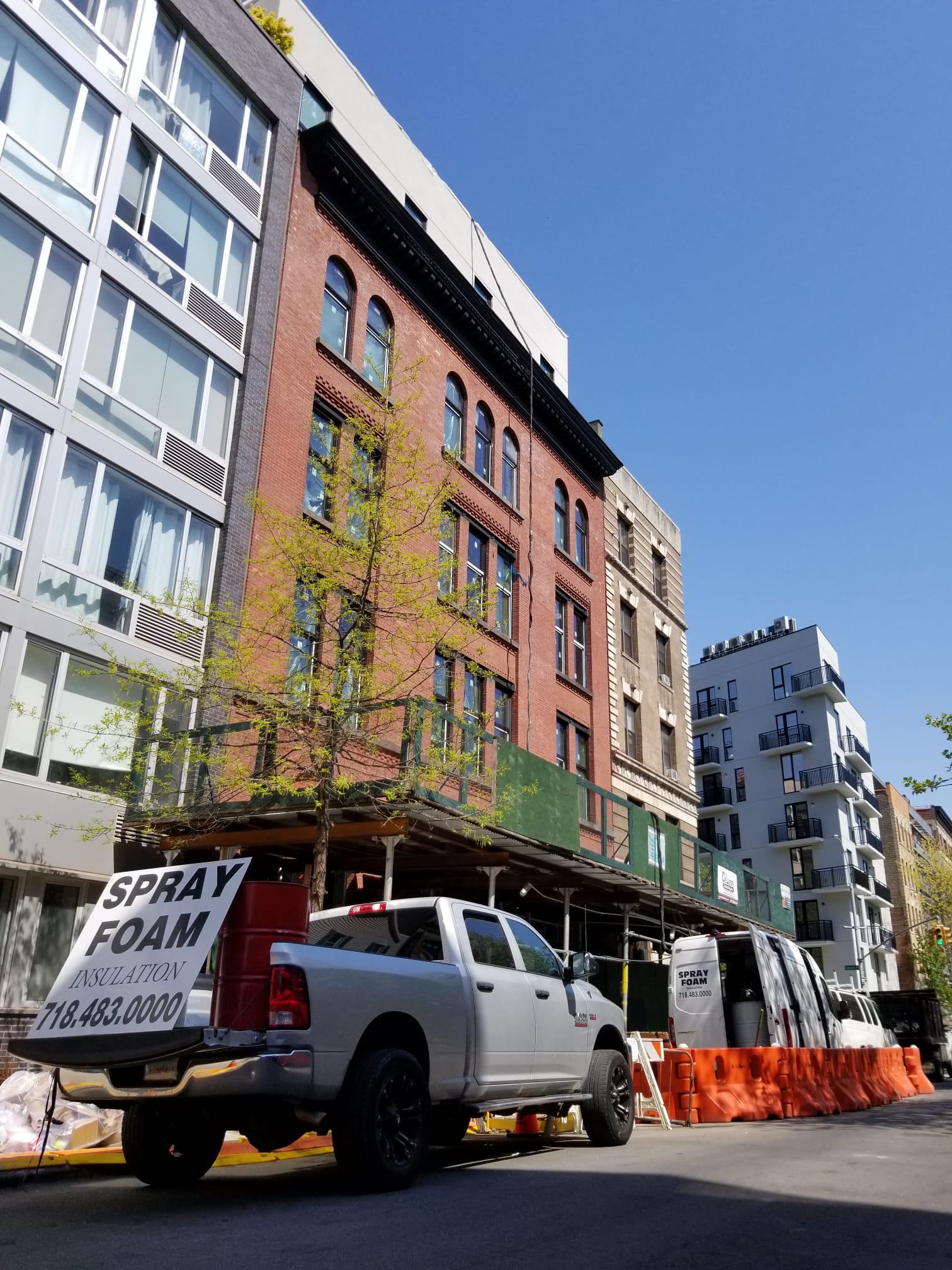 Puza Construction truck and van parked outside a brick building on a New York street