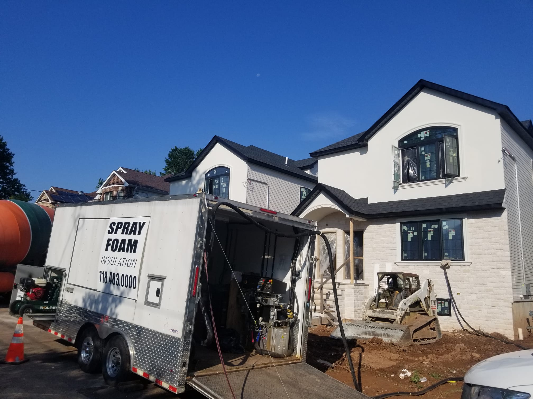 Spray foam trailer parked in front of a new house