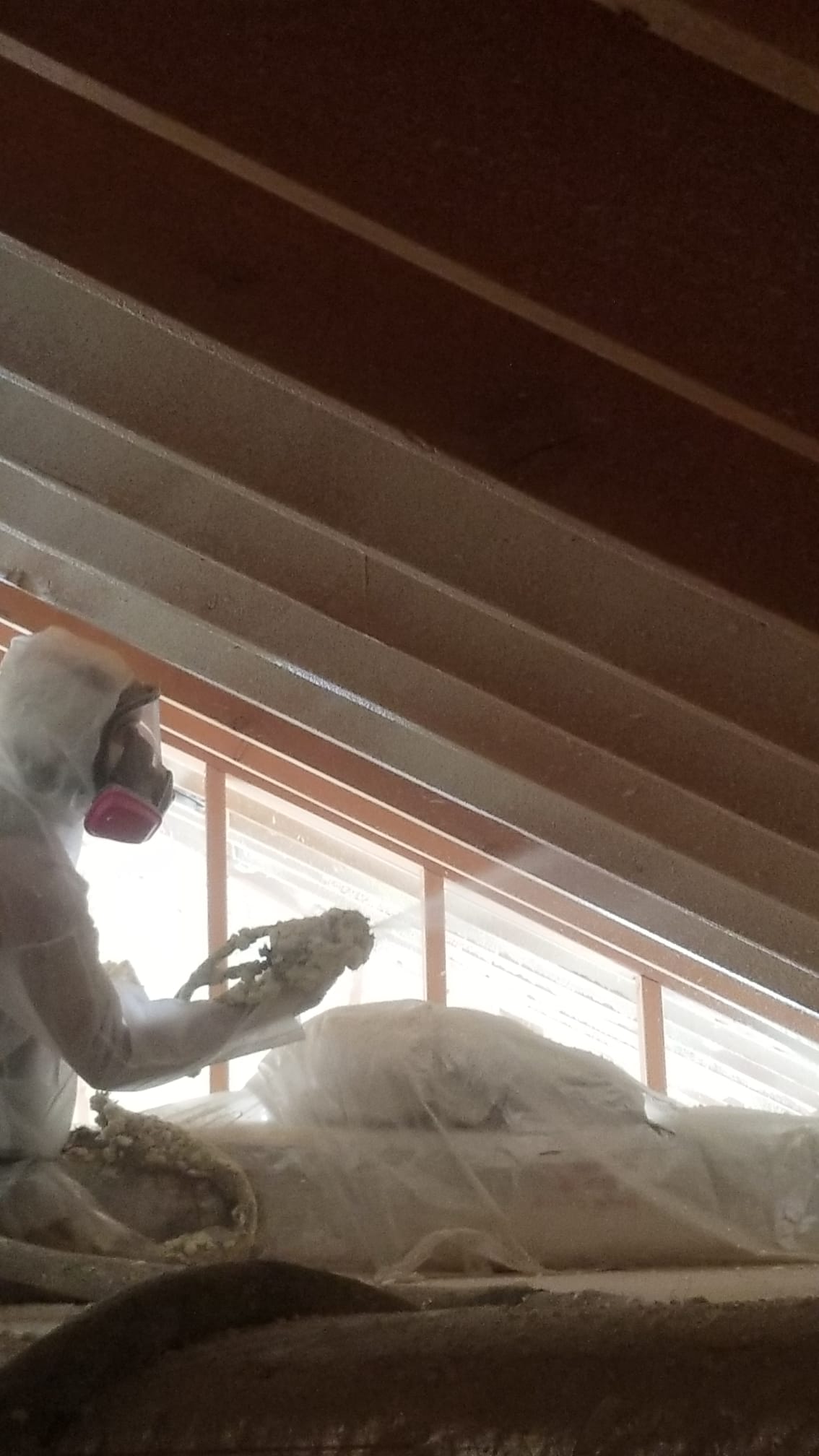 Spraying foam under the roofline of an attic